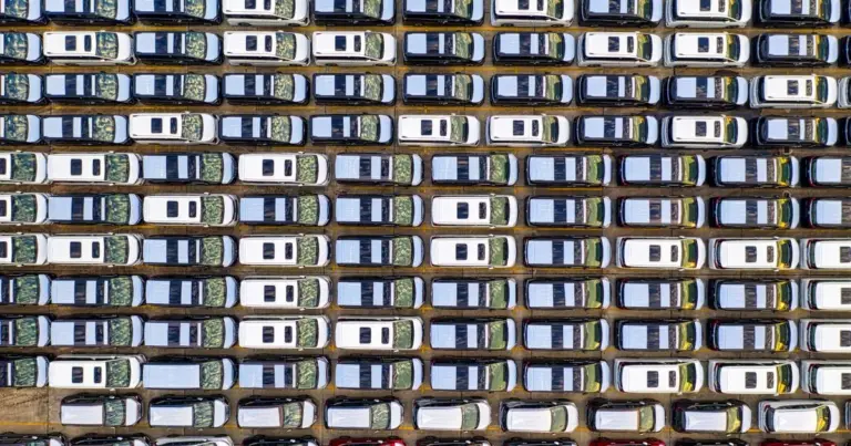 Vista aérea de um grande pátio com muitas fileiras de carros estacionados