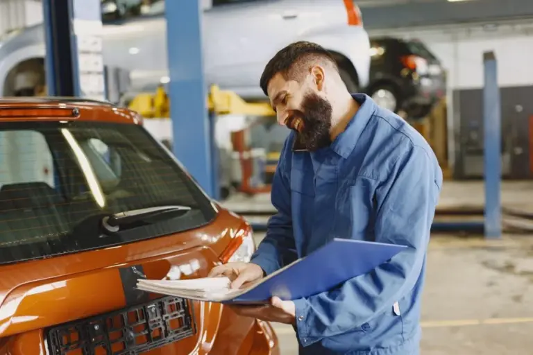 Mecânico inspecionando a lataria de um carro na oficina
