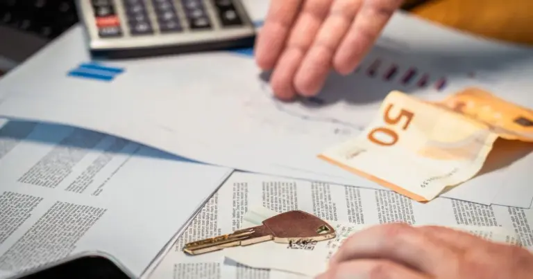 Nota de dinheiro, calculadora e chave de carro sobre papéis em uma mesa, simbolizando o pagamento da venda