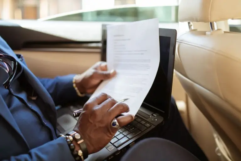 Pessoa conferindo documentos de um carro usado com notebook