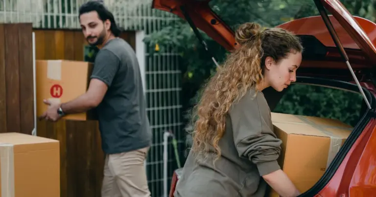 Casal carregando caixas no porta-malas do carro