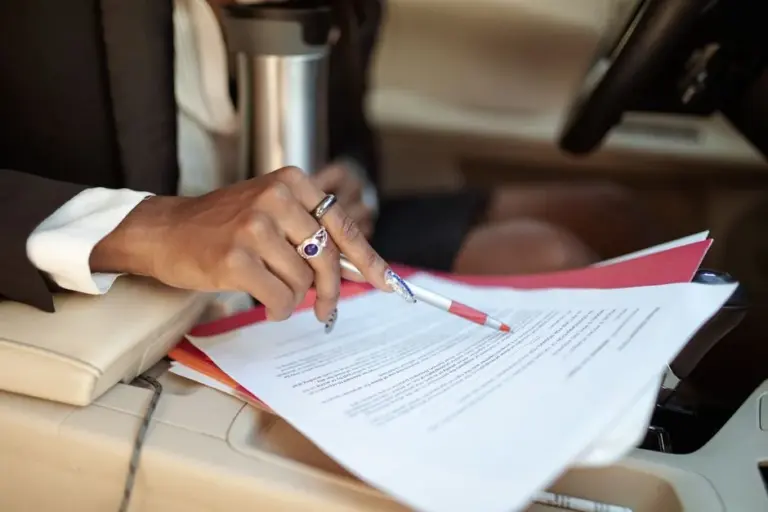 Documentos de carro sendo conferidos por um casal de mãos