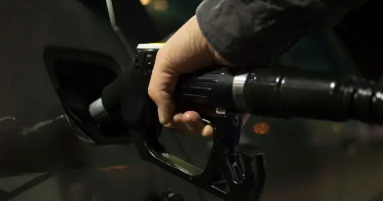 Motorista abastecendo o carro à noite no posto de gasolina