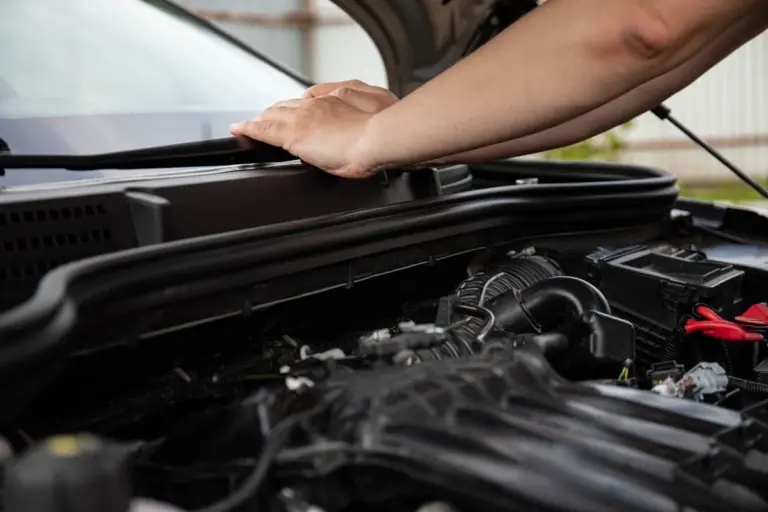 Pessoa abrindo o capô de um carro hatchback usado