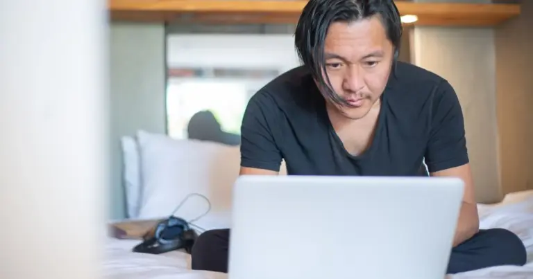 Homem sentado analisando algo com atenção na tela de um notebook