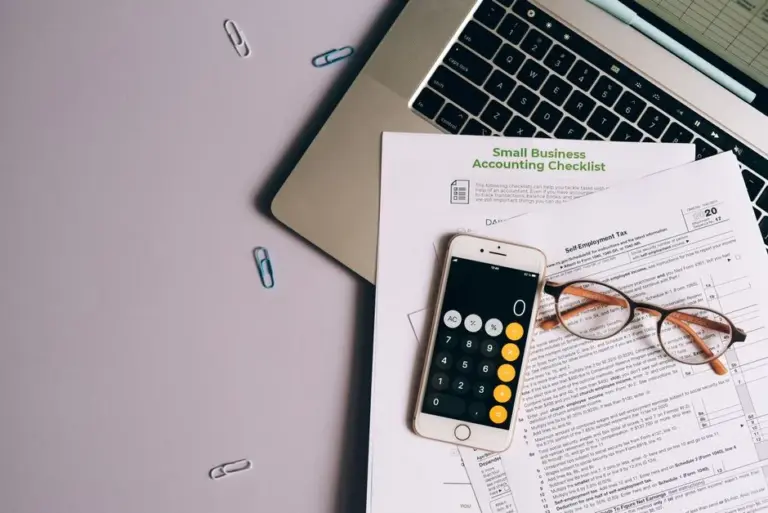 Calculadora e documentos fiscais sobre a mesa com laptop