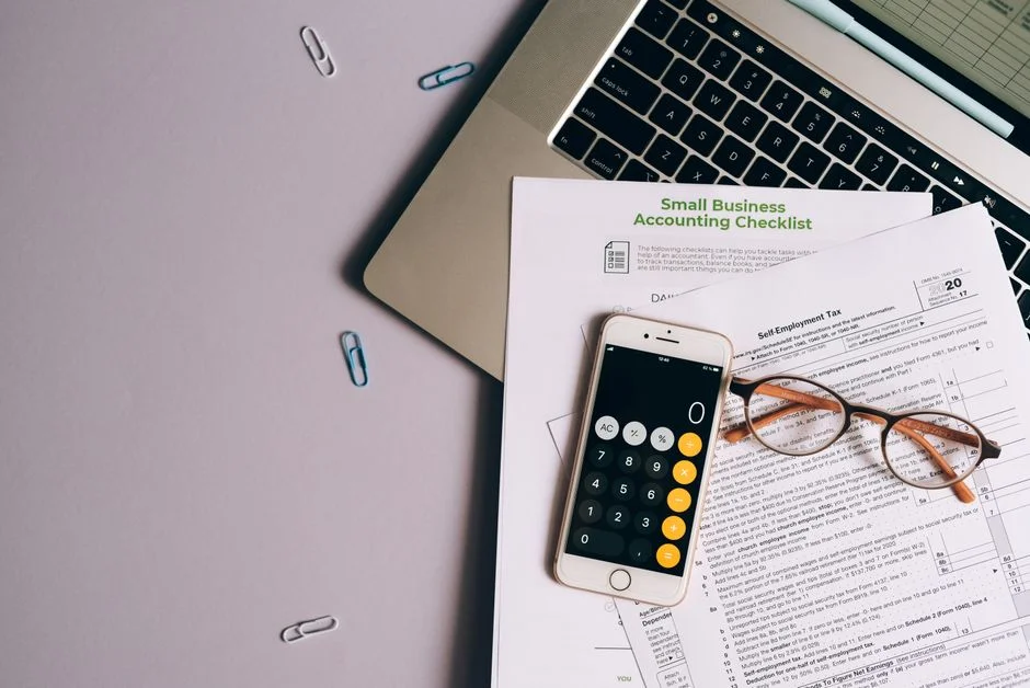 Calculadora e documentos fiscais sobre a mesa com laptop
