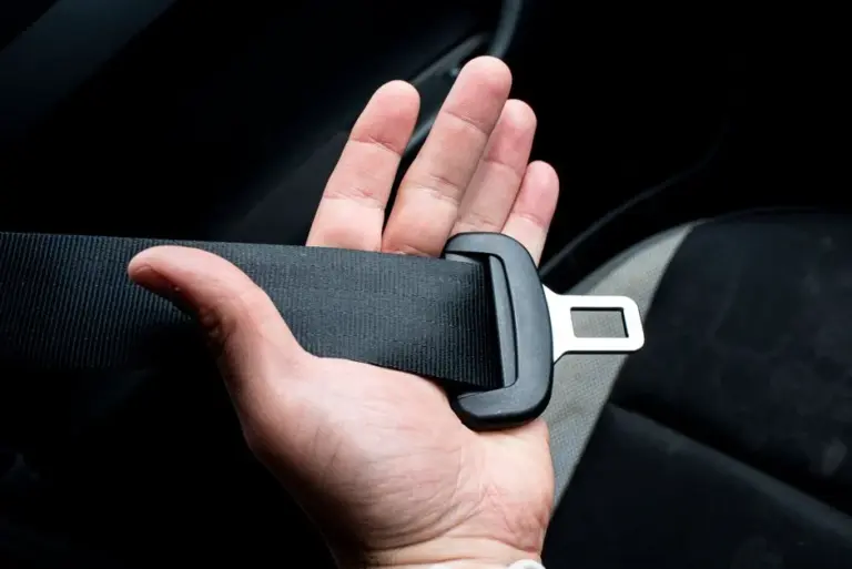 Mão afivelando o cinto de segurança dentro do carro