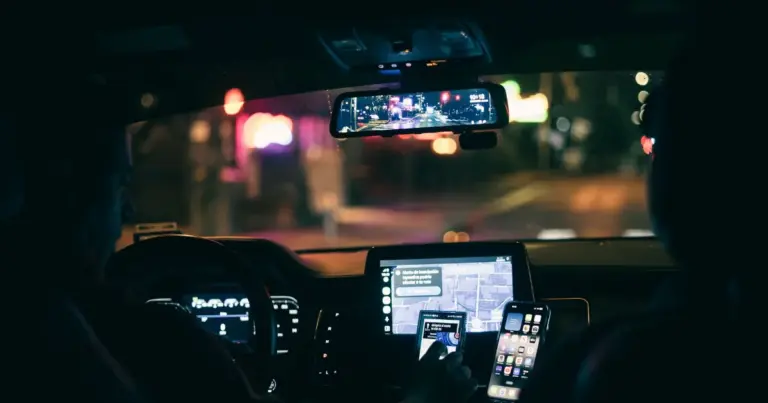 Motorista dirigindo à noite usando o celular para navegação