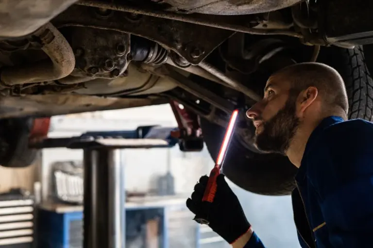 Mecânico fazendo vistoria embaixo de um carro usado