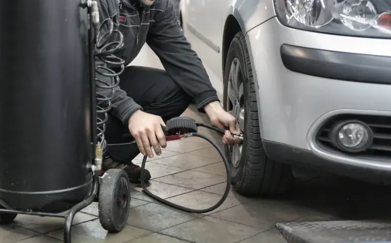 Mecânico calibrando pneu de carro compacto usado