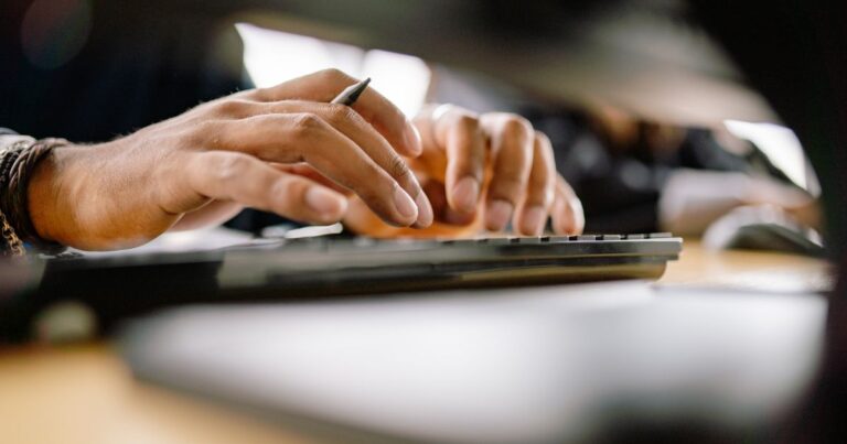 Mãos digitando em um teclado de computador.