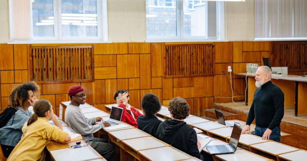 Professor e estudantes adultos participando de uma discussão em sala de aula.